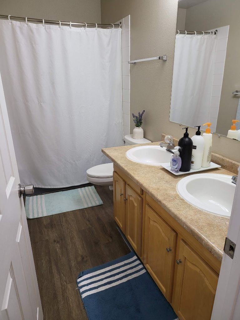 A bathroom with two sinks, a shower, and a toilet.