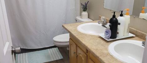 A bathroom with two sinks, a shower, and a toilet.