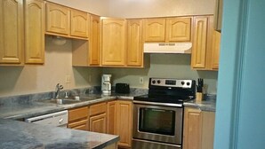 A kitchen with wooden cabinets, a stainless steel oven, a microwave, and a coffee maker. - Sand Lake Jewel - Near Airport, Shopping and the Best Sushi in Town! (Anchorage)