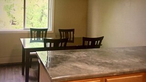 A dining area with a glass-top table and four wooden chairs. - Sand Lake Jewel - Near Airport, Shopping and the Best Sushi in Town! (Anchorage)