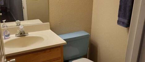 Une petite salle de bain comprenant un lavabo, un miroir, des toilettes et un porte-serviettes.