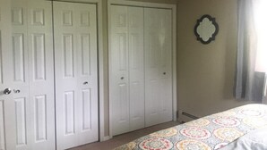A bedroom with two white doors, a patterned bedspread, and a wall-mounted mirror. - Sand Lake Jewel - Near Airport, Shopping and the Best Sushi in Town! (Anchorage)