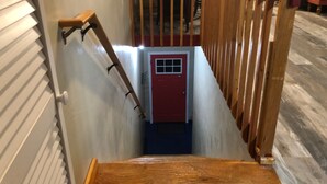 Un escalier avec une rampe en bois et une porte rouge en bas.