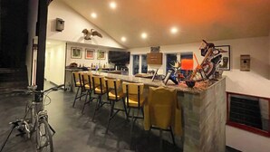 A modern kitchen with a bar area, equipped with bar stools, a large island, and various kitchen appliances.