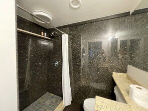Un baño moderno con ducha, inodoro y tocador.