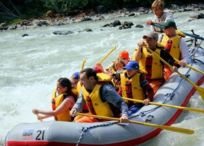 Un grupo de personas en una balsa con chalecos salvavidas, remando en un río.