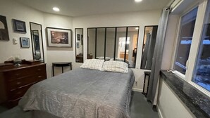 Quarto com cama, penteadeira e um espelho grande.