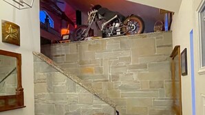 Escadaria de pedra que leva a um patamar onde está estacionada uma motocicleta.