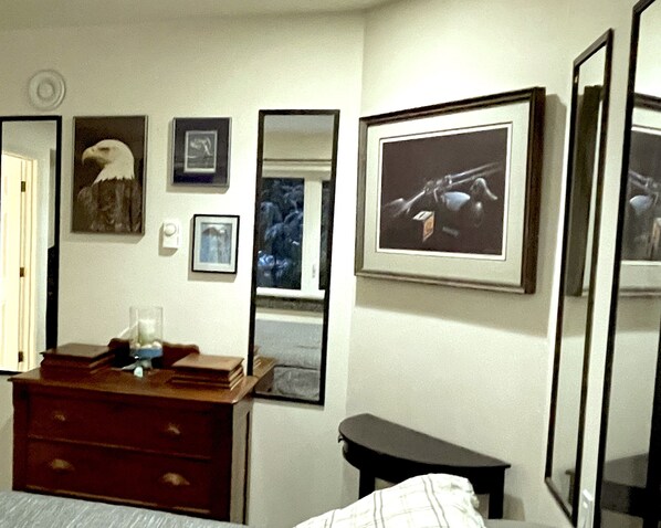 Ein Schlafzimmer mit Bett, Schminktisch und mehreren gerahmten Bildern an der Wand.