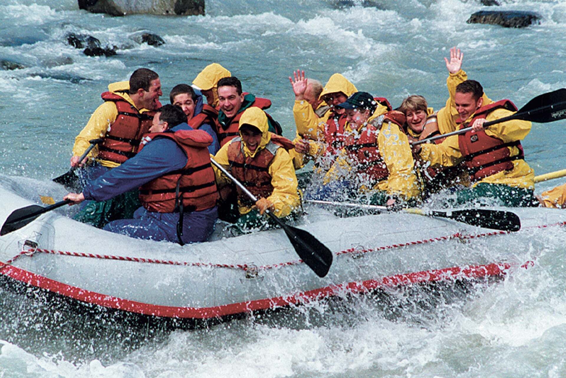 Un grupo de personas en balsas navegando por un río con rápidos.