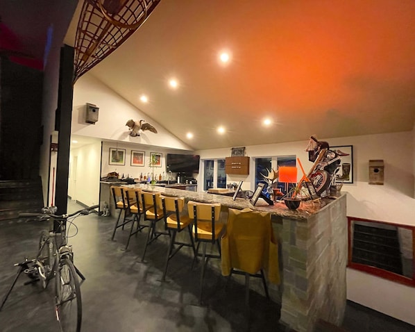A modern kitchen with a bar area, bar stools, and a bicycle.