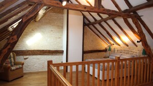 Ein Schlafzimmer mit Holzboden, einem Bett, einem Stuhl und einer weißen Wand.