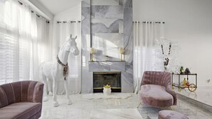 Una sala de estar moderna con una escultura de un caballo blanco, chimenea y asientos cómodos.