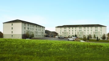 Stunning hotel with a central entrance and flat roof, set amidst a grassy area.