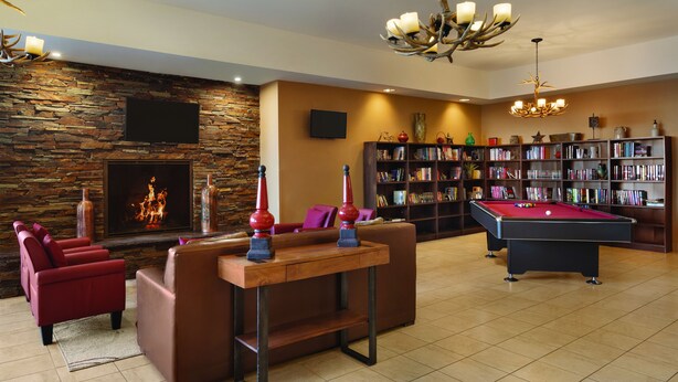 Ein großzügiges Wohnzimmer mit Kamin, Billardtisch, Ledersofas und Bücherregal.