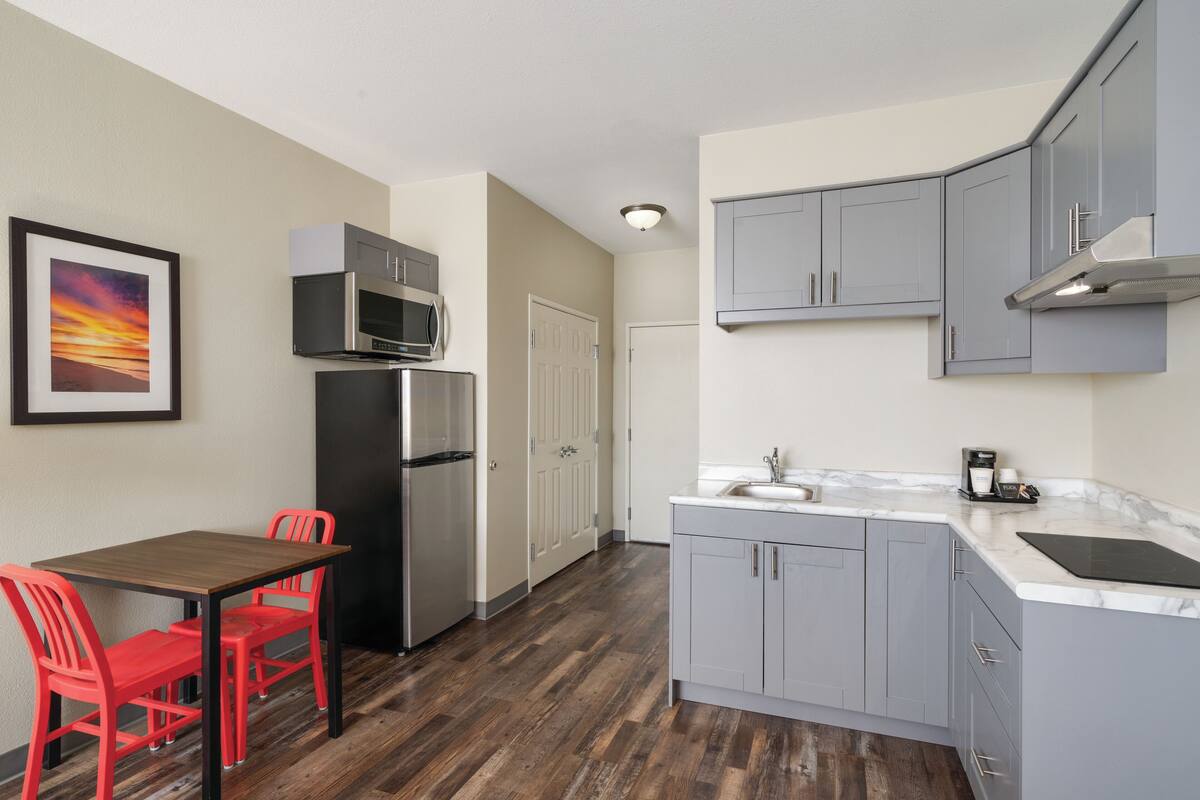 Cocina compacta con zona de comedor, que incluye refrigerador, microondas y pileta.