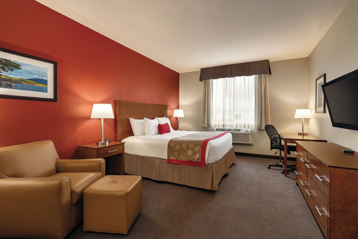 Una habitación de hotel con una cama, un escritorio, una silla, un sofá y un televisor.
