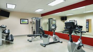 Un gimnasio con equipo de ejercicio, un espejo grande y una pared de acento roja.