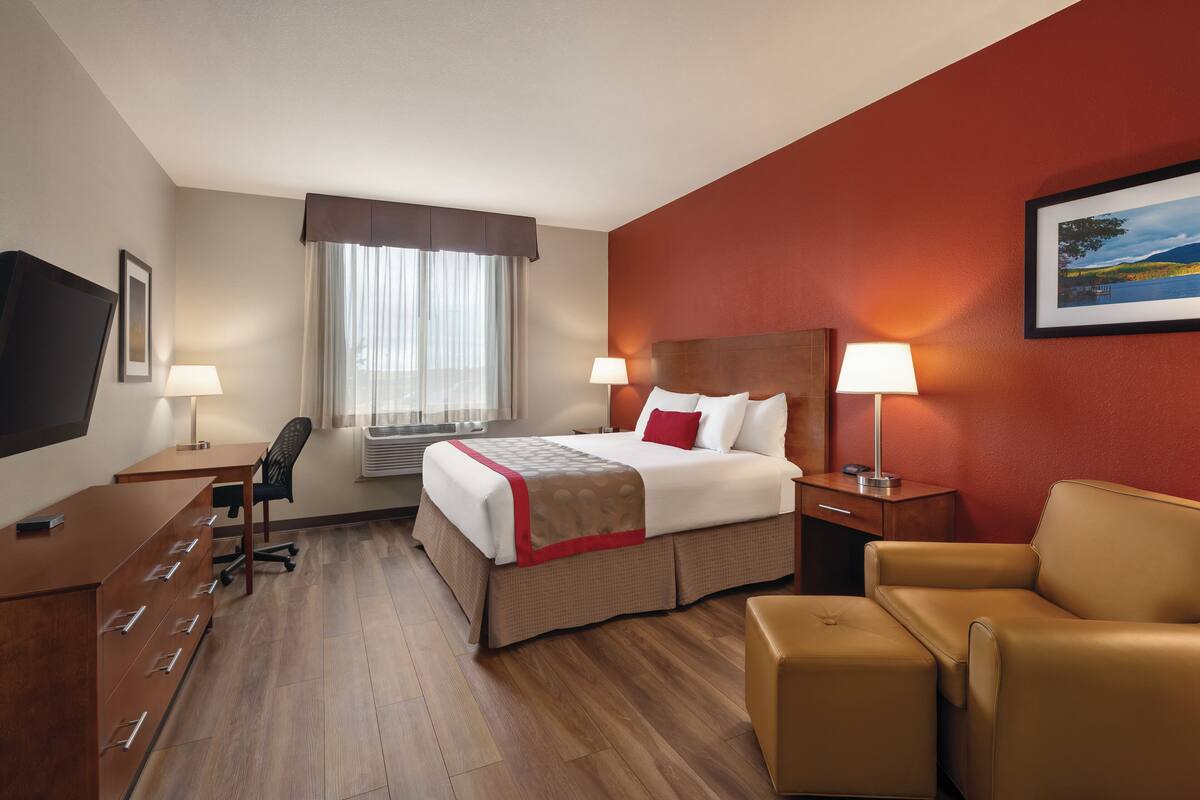 Una habitación de hotel con cama, escritorio, silla y televisor.