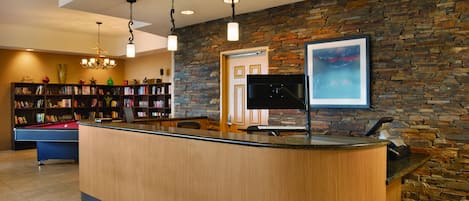 A reception area with a wooden reception desk, a pool table, and a bookshelf filled with books.