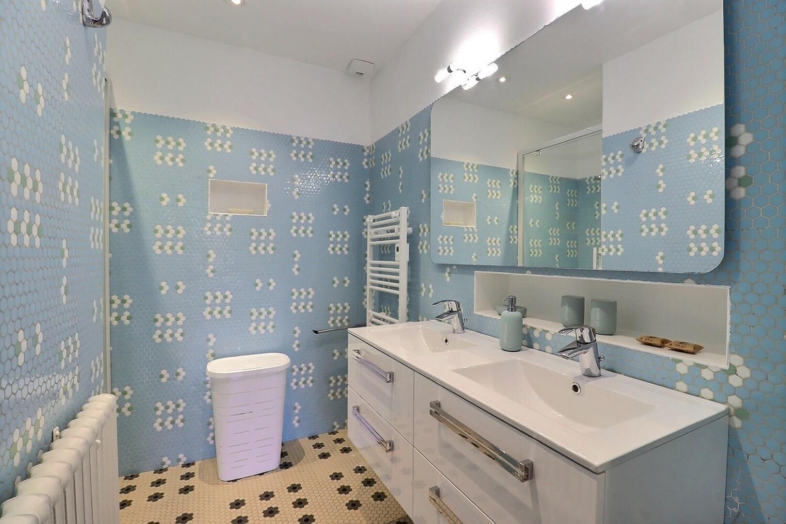 Ein Badezimmer mit einem Doppelwaschbecken, einem Spiegel, einer Toilette und einer Duschkabine.