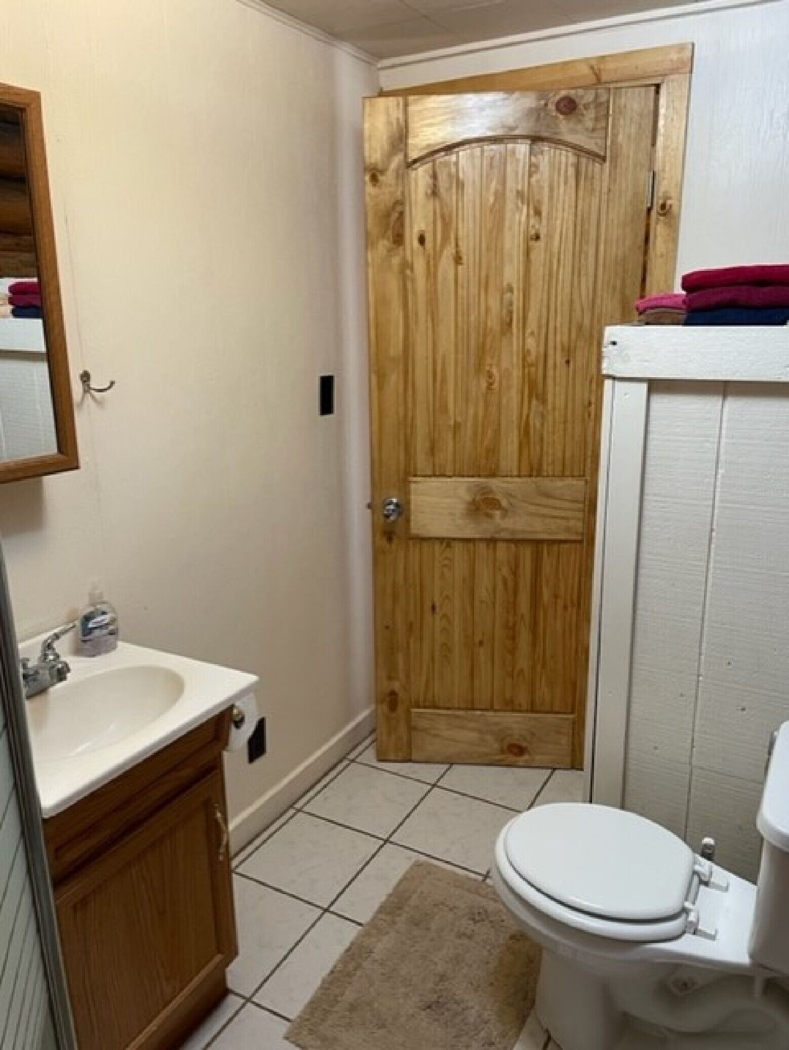 A bathroom with a wooden door, a white sink, and a toilet.