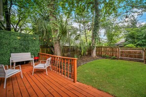 Relax on the deck surrounded by lush greenery and a wooden fence.