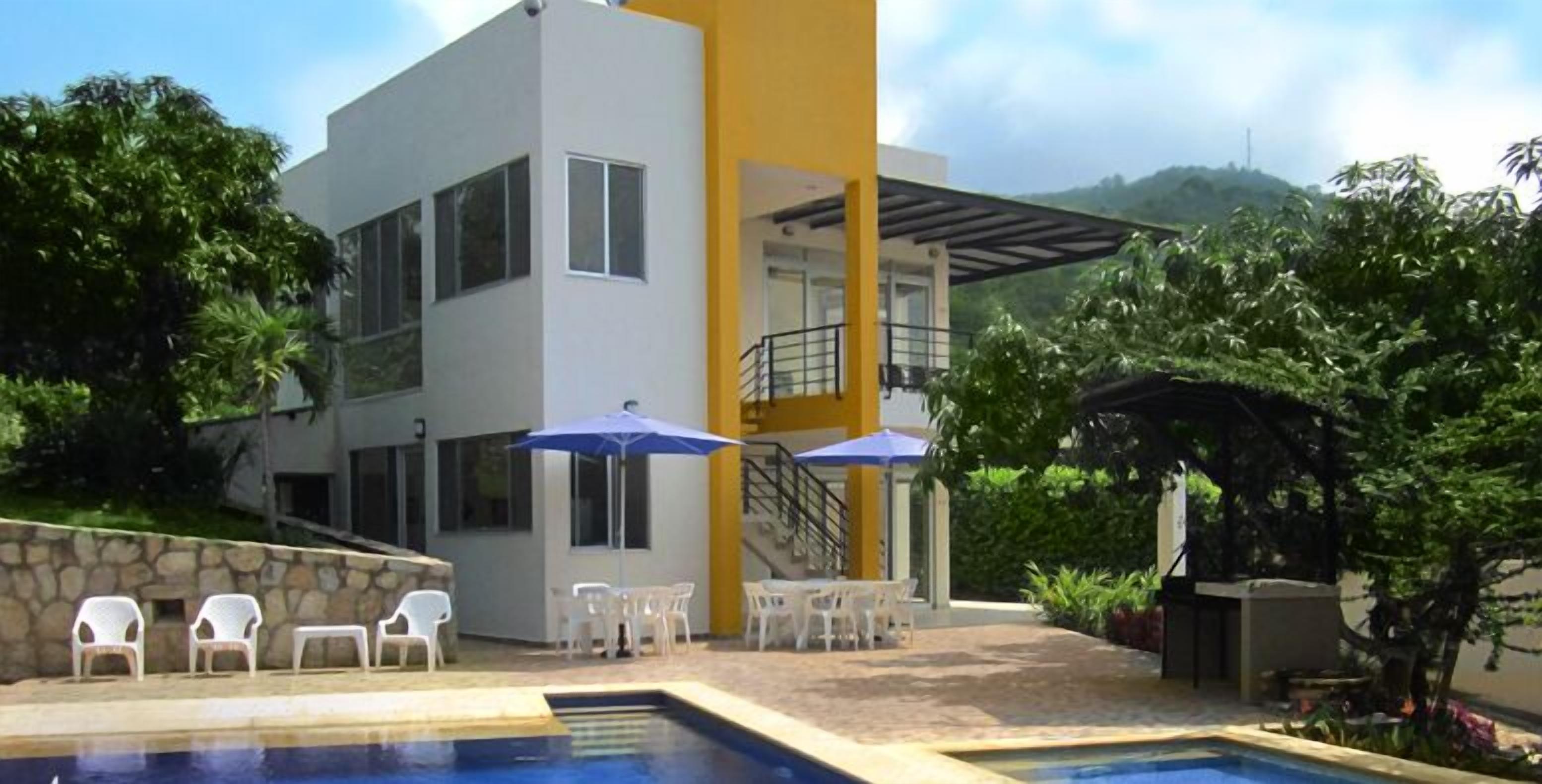 A modern two-story building with a swimming pool, outdoor seating, and a covered patio area.