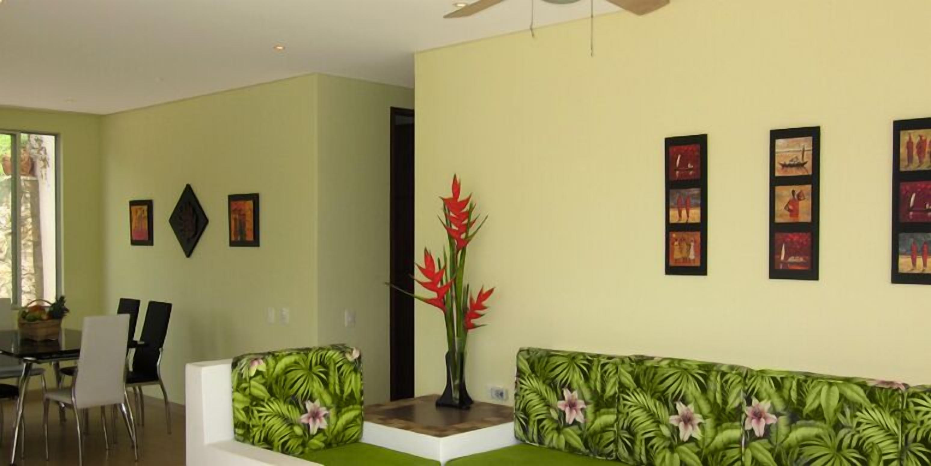 Una sala de estar con un sofá verde, una mesa de centro y una zona de comedor con sillas y una mesa.