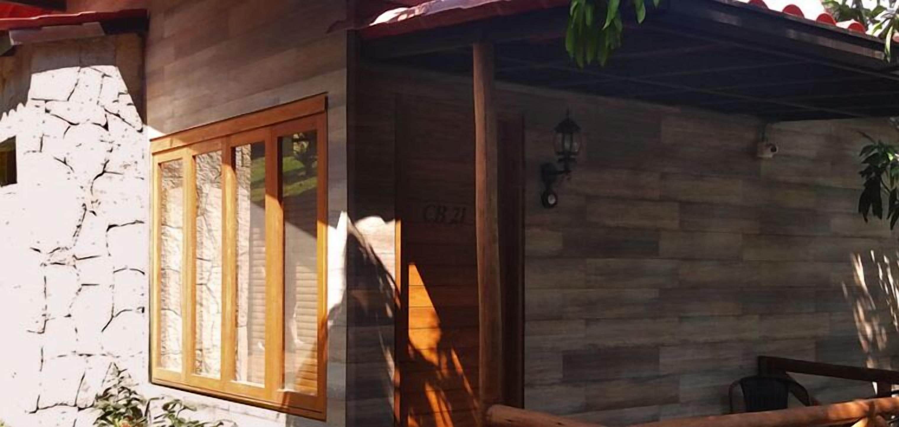 A rustic building with a stone facade, a wooden door with glass panels, and a small porch area with a lantern.