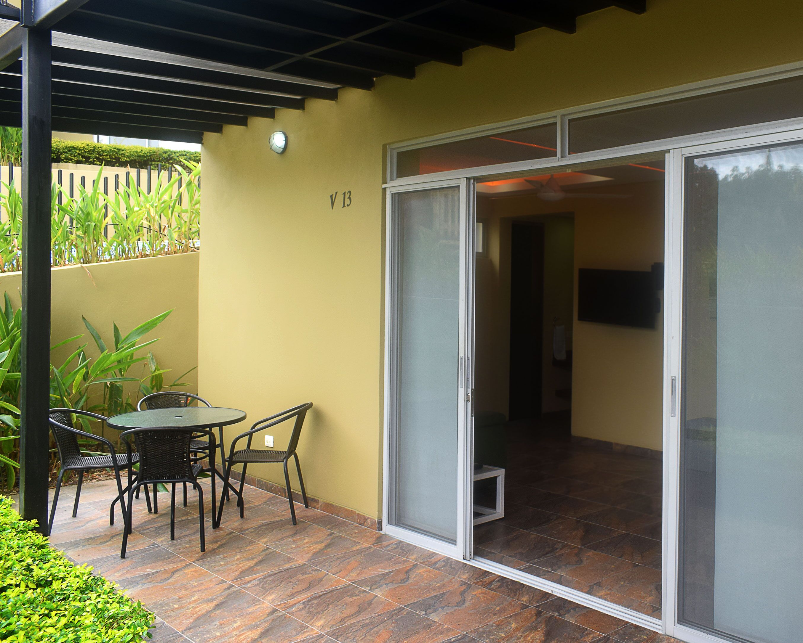 A patio with a table and chairs, a sliding glass door, and a wall with a number sign.