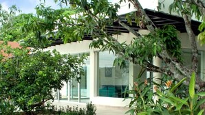 Un edificio moderno con fachada de vidrio, rodeado por un jardín ajardinado con diversas plantas y un sendero curvo.