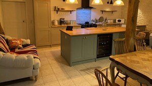 Una cocina acogedora con una isla central, sillas de madera e iluminación colgante.