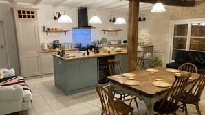 Una cocina amplia con una isla central, sillas de madera y una mesa de comedor para seis personas.
