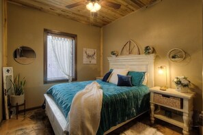 A bedroom with a bed, bedside table, lamp, and a window with curtains. - Stunning home on 7 acres with 5400sf of indoor/outdoor living space (Hermosa)