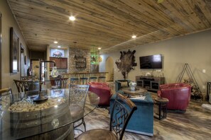 A spacious living room with a high ceiling, a stone wall, a large TV, and a bar area with stools.