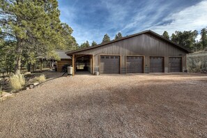 A large, single-story building with a gravel driveway and a covered entrance. - Stunning home on 7 acres with 5400sf of indoor/outdoor living space (Hermosa)
