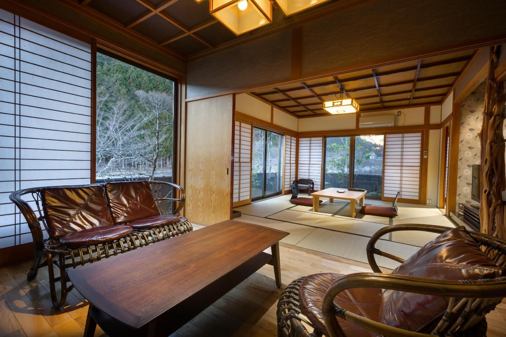 A traditional Japanese room with tatami flooring, a low wooden table, and a cushioned seating area.
