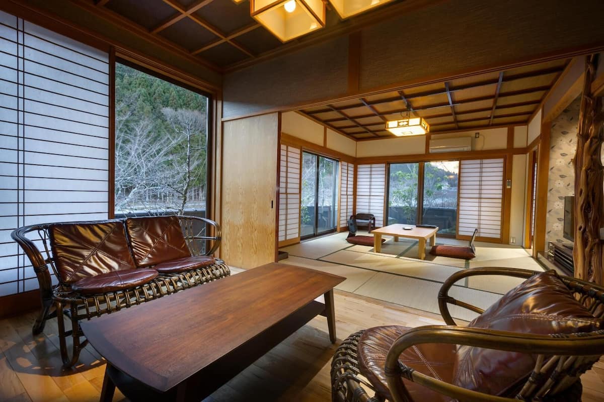 A traditional Japanese room with tatami flooring, a low wooden table, and a cushioned seating area.