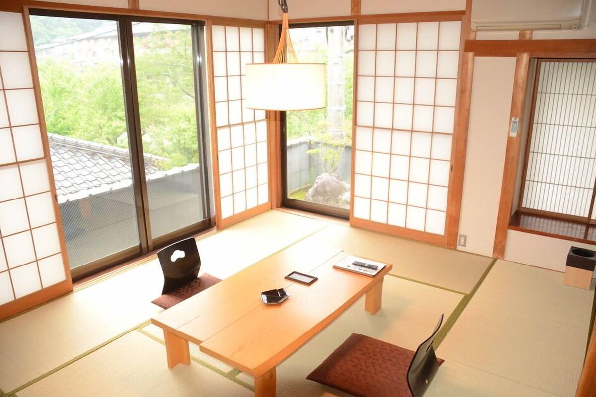 A traditional Japanese room with tatami flooring, a low table, a chair, and sliding doors.