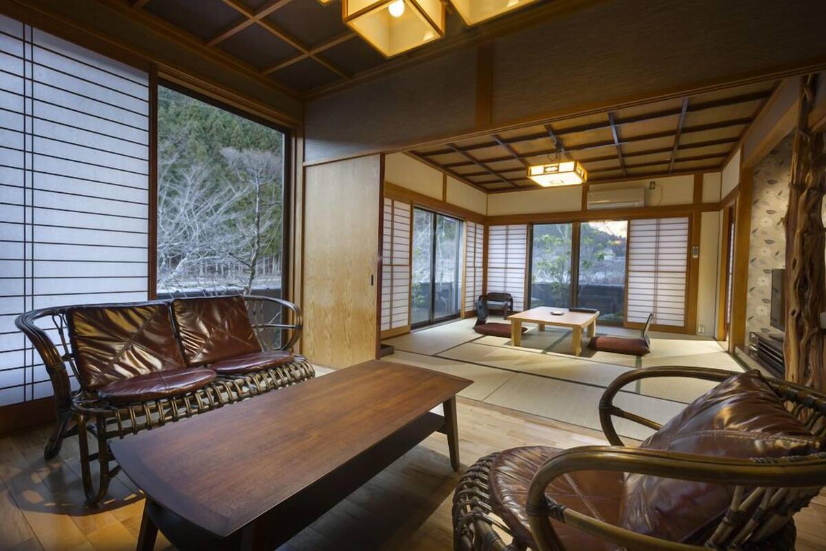 A traditional Japanese room with tatami flooring, a wooden table, and a sofa.