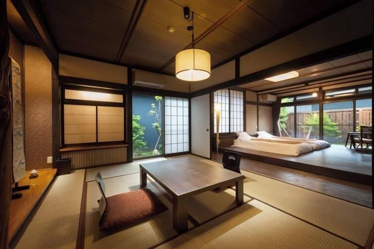 A traditional Japanese room with tatami flooring, a low table, a sofa, and large windows.