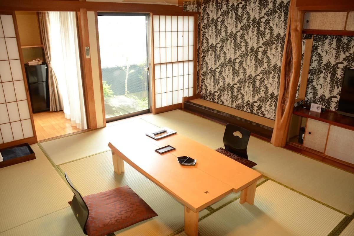 A traditional Japanese room with tatami flooring, a low table, and sliding doors.