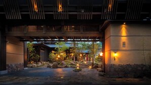 A traditional Japanese-style building entrance with a stone pathway, wooden beams, and lanterns. - Kurotake (Achi)