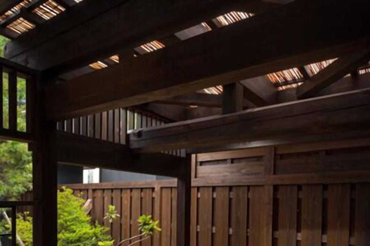 Un bain à remous sous une pergola en bois, avec une clôture en bois en arrière-plan.