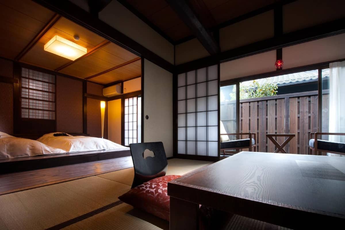 A traditional Japanese room with tatami flooring, a low table, a cushioned bench, and sliding doors.