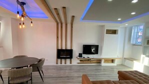 Een moderne woonkamer met een televisie, houten balken en een bank.