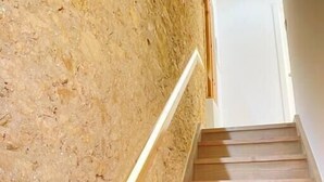 Een houten trap met een gestructureerde wand aan één kant.
