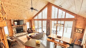 Un intérieur de cabine spacieux comprenant un grand coin repas, un salon confortable et une cheminée en pierre.
