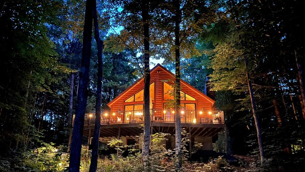 Une cabane en bois dotée d’un balcon, entourée d’arbres.